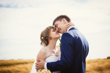 young bride and groom on the background of field