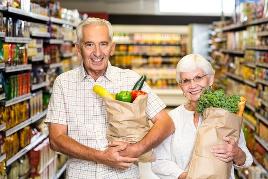 Smiling senior couple holding grocery bags