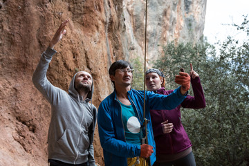 Group of Climbers belays Leader with Mature Coach in the middle