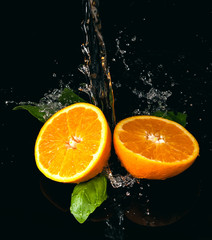 Pomarańcze polane wodą na czarnym tle - obrazy, fototapety, plakaty