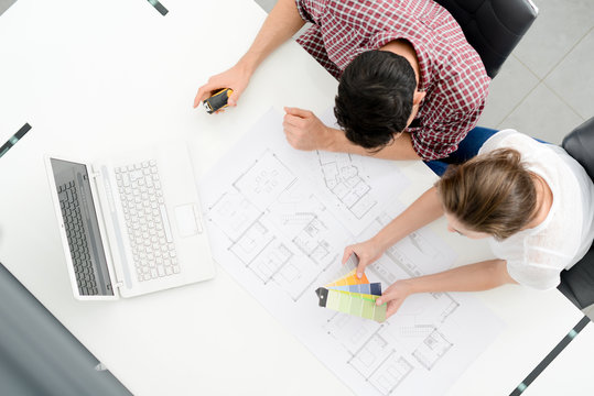young couple planning decoration project of their new home with blueprint
