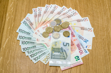 Euro banknotes and euro coins on wooden table