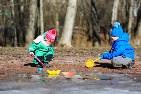 little boy and girl playing with water in spring