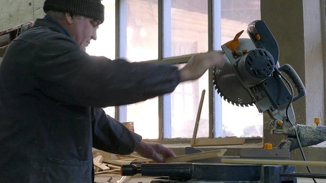 Столяр пилой отрезает доску