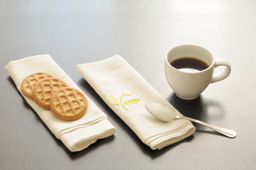 colazione 
una tazzina di caffè, tre biscotti su un tovagliolino di stoffa e un cucchiaino di...