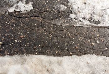 Snow on damaged asphalt.