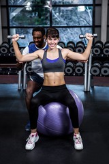 Fototapeta na wymiar Male trainer helping woman during dumbbells exercise