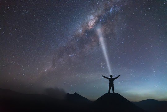 A person is standing next to the Milky Way galaxy spread hand on