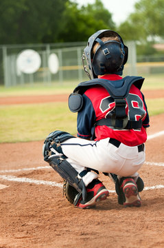 Young baseball catcher behind home base.