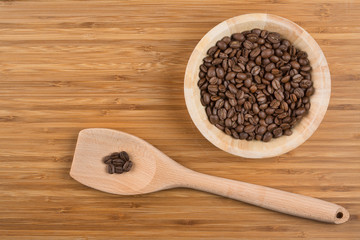 Coffee beans in bowl on wooden background