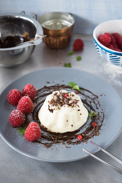 Beautiful styling of vanilla panna cotta with chocolate sauce and fresh raspberries