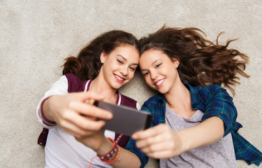 happy teenage girls on floor and taking selfie