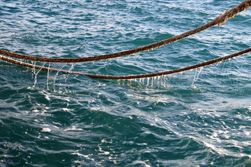 Old torn boat ropes above the sea water