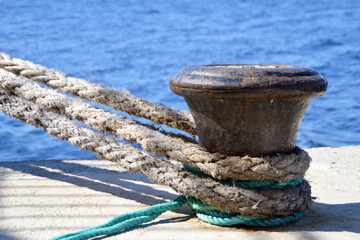 Fototapeta na wymiar Detail of thick boat ropes tied to an old rusty bollard