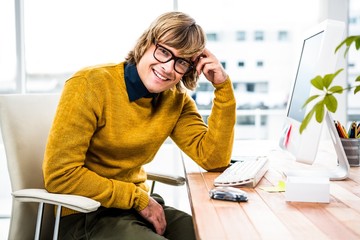 Obraz na płótnie Canvas Smiling hipster businessman sitting at his desk