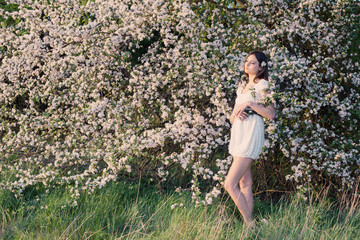 Beautiful young girl on background flowering apple-tree