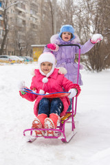 The girls in the courtyard of riding a snow sled rejoice