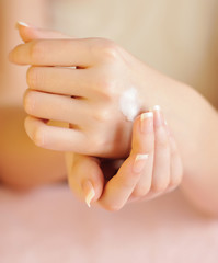 Naklejka premium Young woman applies cream on her hands after bath. Focus on hand