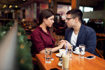 Lovely young couple looking at each other at cafe in trade center. Copy space for your text. Shallow depth of field. Very useful photo for processing with one click on edit image.