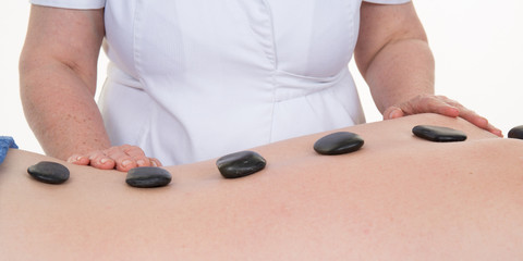 Man laying on massage bed with hot stones at spa center