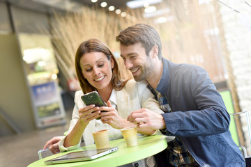 Couple sitting at coffee shop and using smartphone