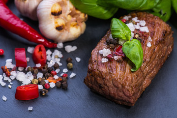 Beef Steak, salt, pepper, garlic, rosemary  on the black board, background.