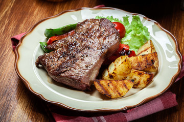 Portions of grilled beef steak with grilled potatoes and paprika