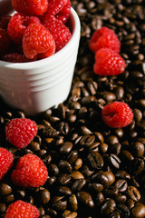 Raspberries in a white cup on coffee beans