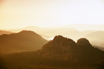 Sunrise in a beautiful mountain of Czech-Saxony Switzerland. Sandstone peaks increased from foggy background