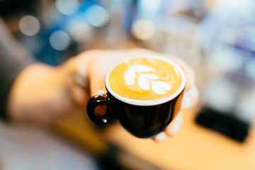 Closeup of barista holding cup of coffee with flower shape