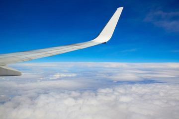 Aircraft wing flying in blue sky and clouds