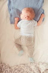 Baby boy lying in bed. Top view. Kid sleeping in room. Childhood. Bedtime. Healthy lifestyle.