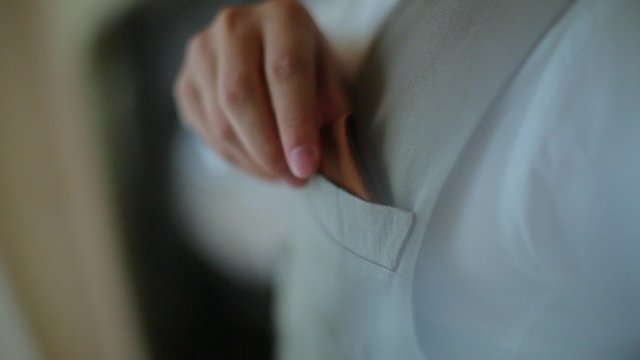 The guy puts the handkerchief in his pocket vest.