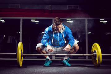 Handsome weightlifter preparing for training. Shallow depth of field, selective focus on hands and dust.