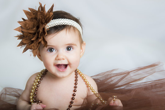 Bebé niña sonriente vestida de bailarina con un tutú marrón y adornos en el pelo