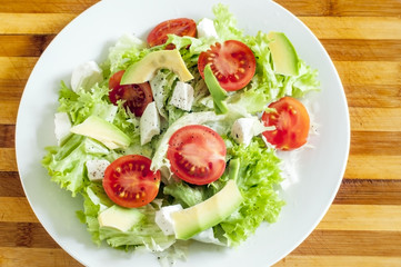 Свежий салат на тарелке и деревянной доске