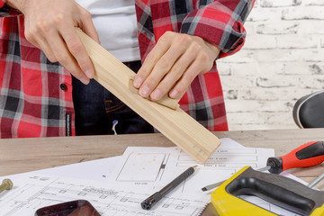 Fototapeta na wymiar young carpenter sanding a wooden board