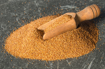 Teff an ancient grain with a wooden scoop on black slate
