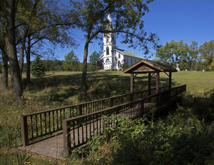 Fototapeta na wymiar Rural white church in a sunny meadow.