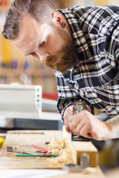 Carpenter work with planer on wood plank in workshop