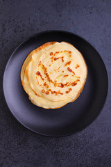 pancakes with apple and nuts on a black plate on a black background