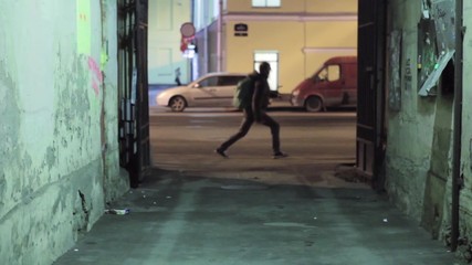 Back side of running man with green backpack out of courtyard. He run on right.