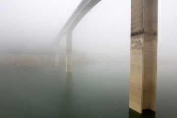 Un viaduc au dessus de l'eau dans le brouillard