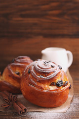 buns with raisins and powdered sugar on a dark wooden background