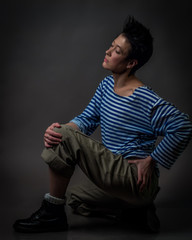Androgynous character in a striped vest on a gray background