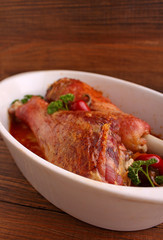 Baked turkey legs in white plate on dark background