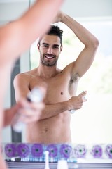 Obraz premium Handsome shirtless man putting deodorant