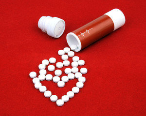 The tablets from heart disease spill out of boxes on a red velvet. Tablets are scattered in the...
