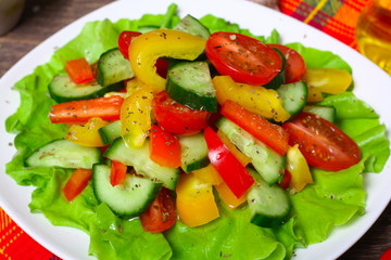 Helpful Fresh Salad of cucumbers, tomatoes, pepper and lettuce dressed with olive oil.