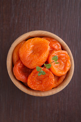 dried apricots in a wooden bowl with mint leaf